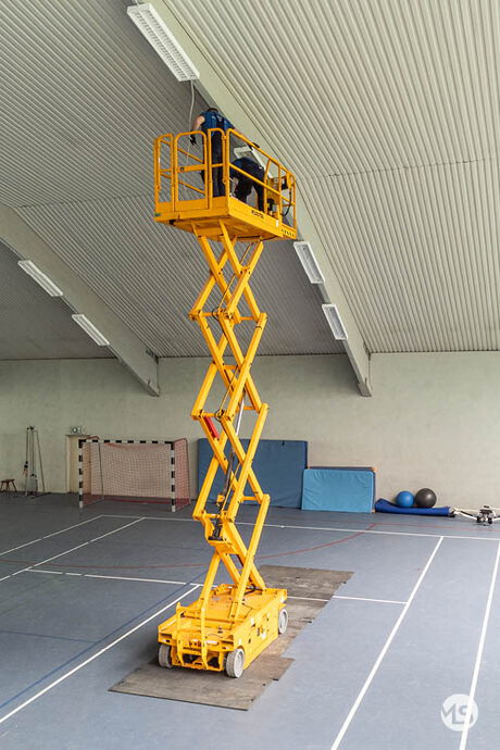 Elektriker von Marquardt & Streck arbeiten mit der Hebebühne an der Hallenbeleuchtung