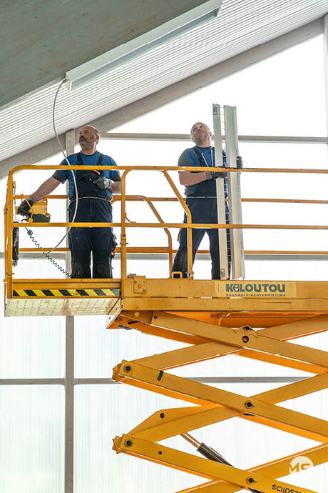 Marquardt & Streck Elektriker auf einer Hebebühne bei Elektroarbeiten in einer Turnhalle