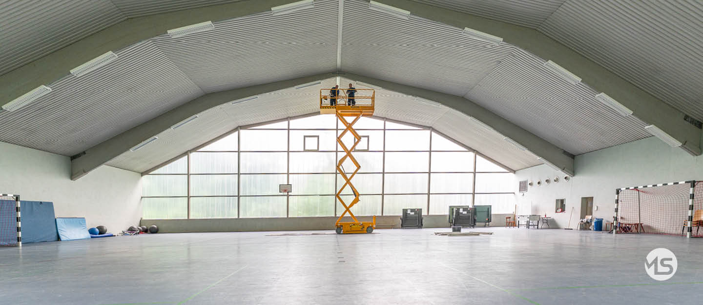Elektriker von Marquardt & Streck erneuern die Beleuchtung unter dem Hallendach einer Turnhalle
