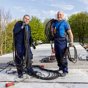 Zwei Elektriker arbeiten gemeinsam auf einem Dach bei der Montage