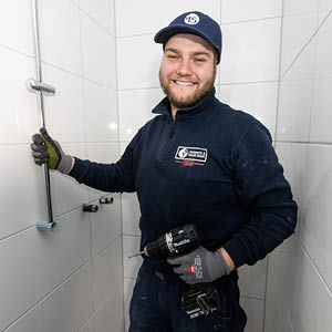 Monteur richtet eine Duschstange aus und befestigt sie präzise.