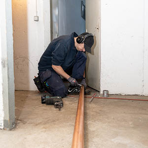 Verlegung eines Kupferrohrs im Kellergang.