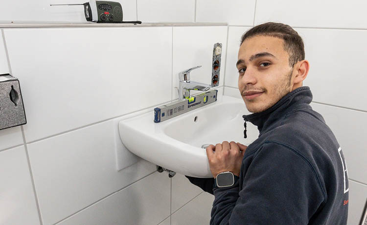 SHK Azubi bei einer Waschtisch-Montage.